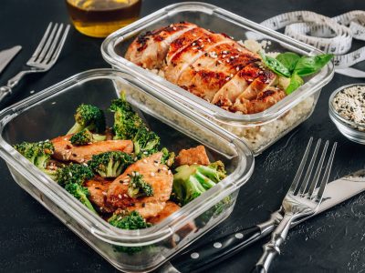 KETO WEIGHT-LOSS grilované kuře s květákovou rýží a kuřecím masem a brokolicí v sójové omáčce se sezamem na černém stole.